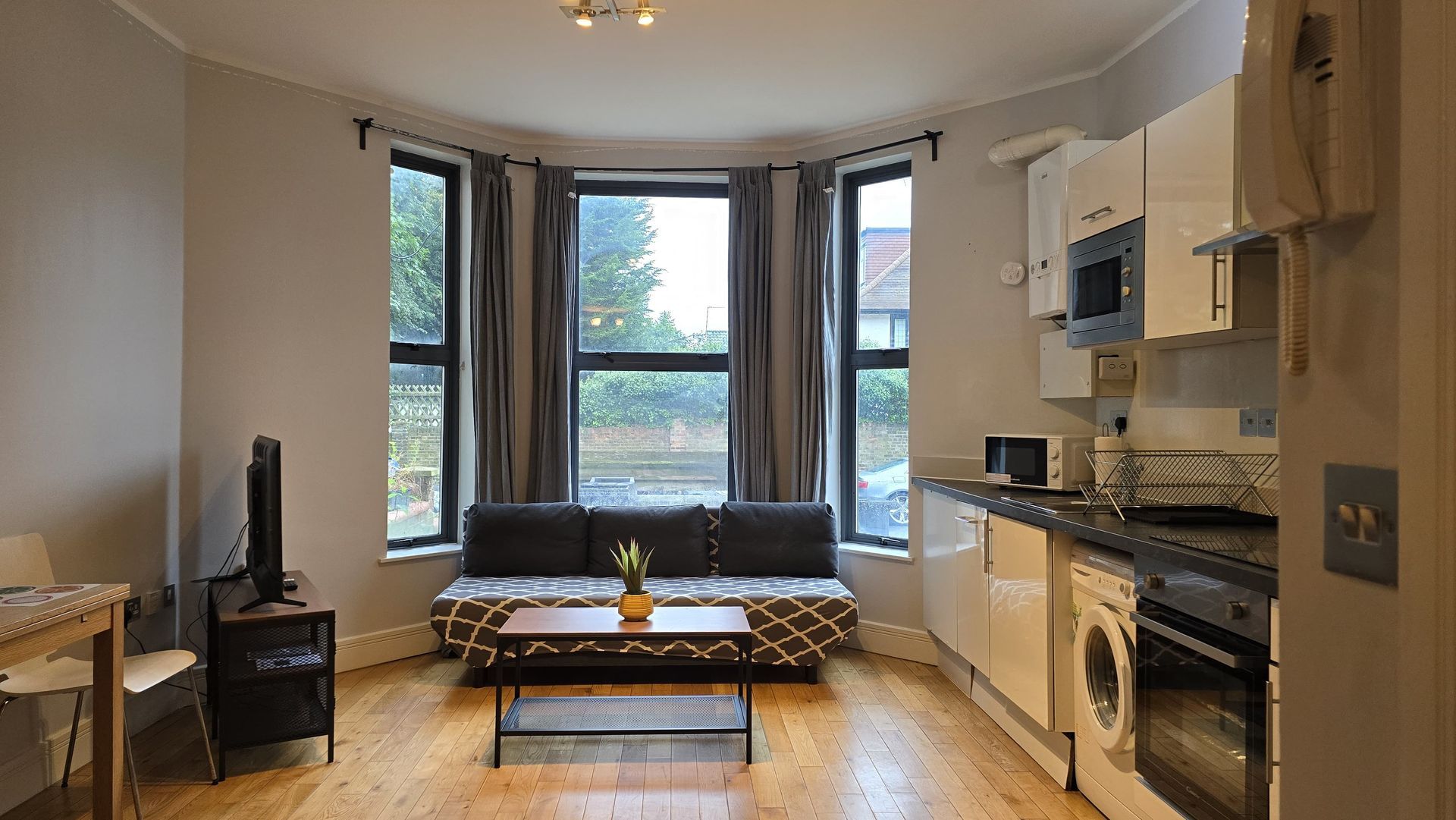 A living room with a couch , table , television and a kitchen.
