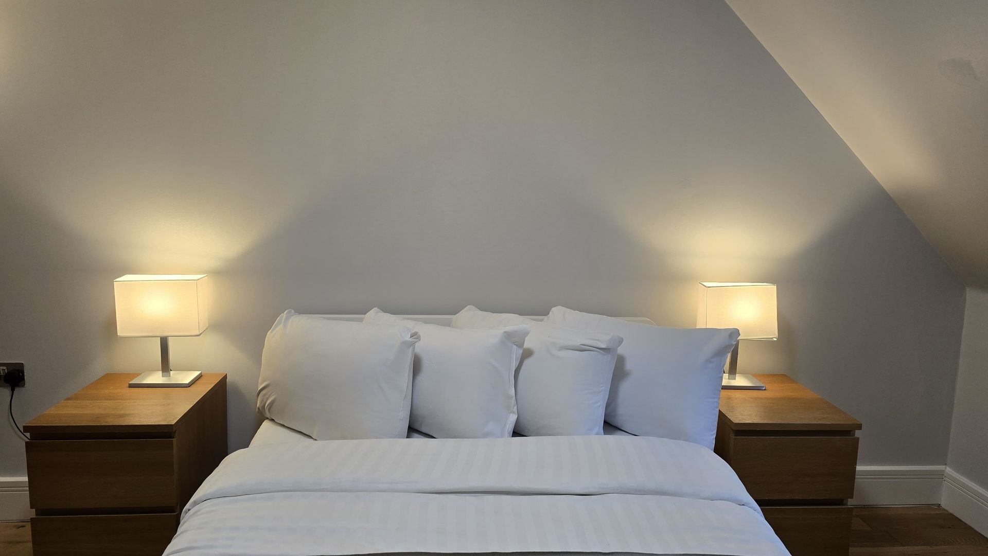 A bedroom with a bed , two nightstands and two lamps