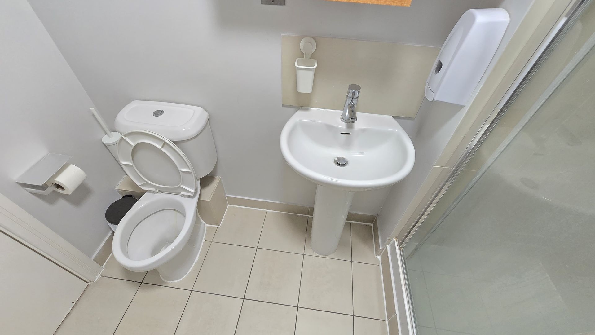 A bathroom with a toilet , sink and shower.