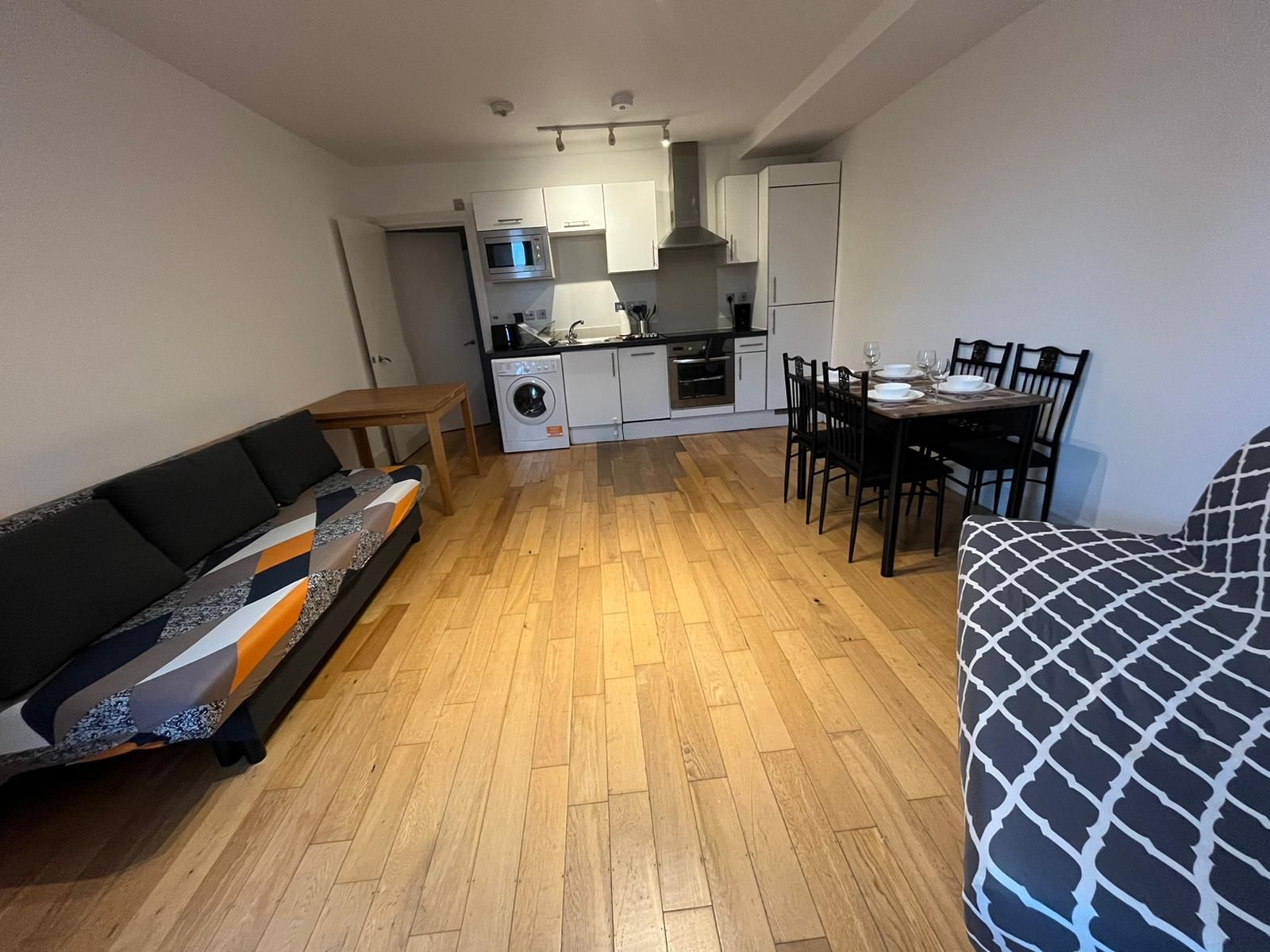 A living room with hardwood floors , a couch , a table and chairs.