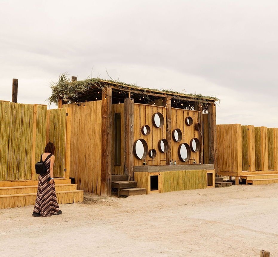 Una mujer parada frente a un edificio de madera con espejos en la pared.
