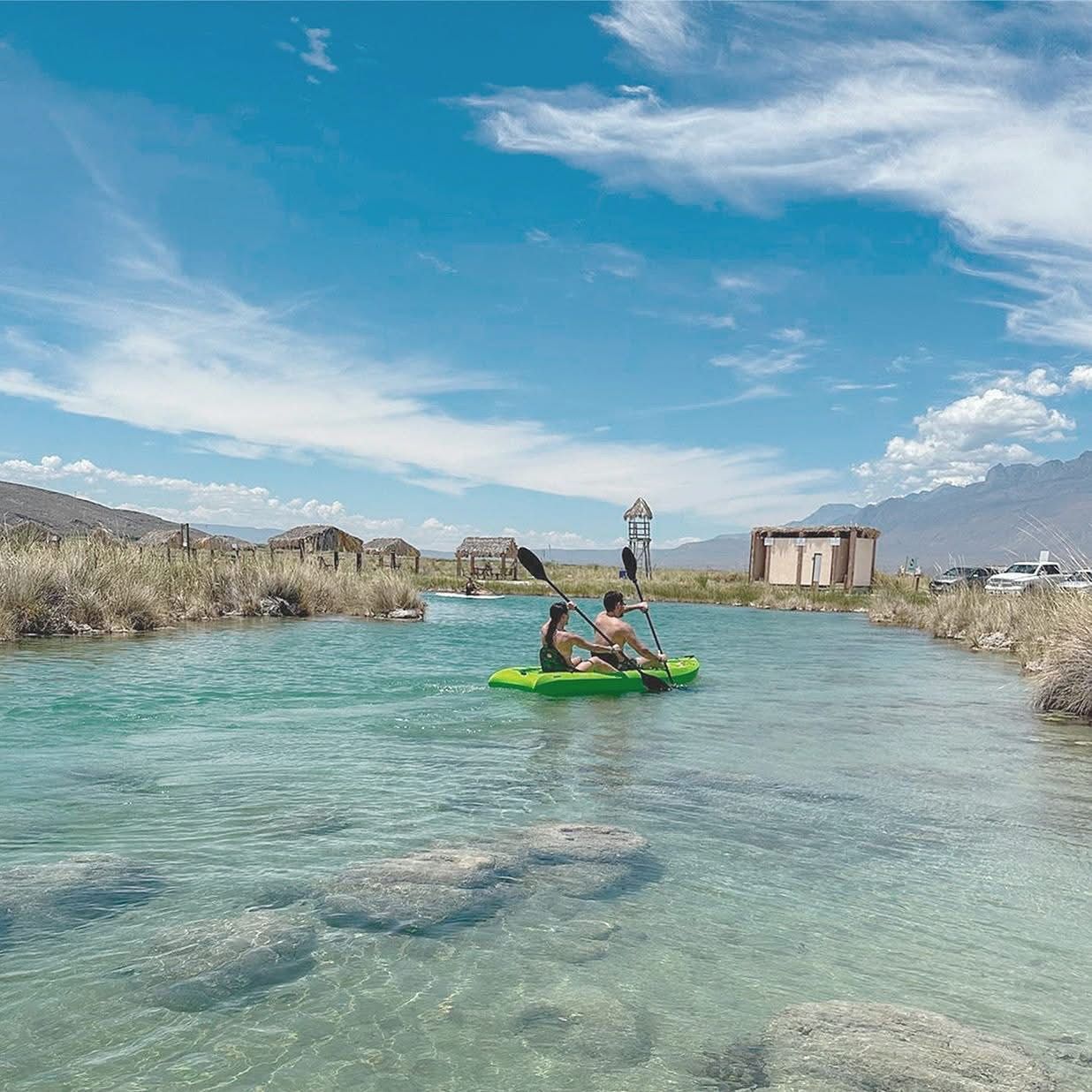 Un hombre y una mujer están remando en un kayak verde en un río.