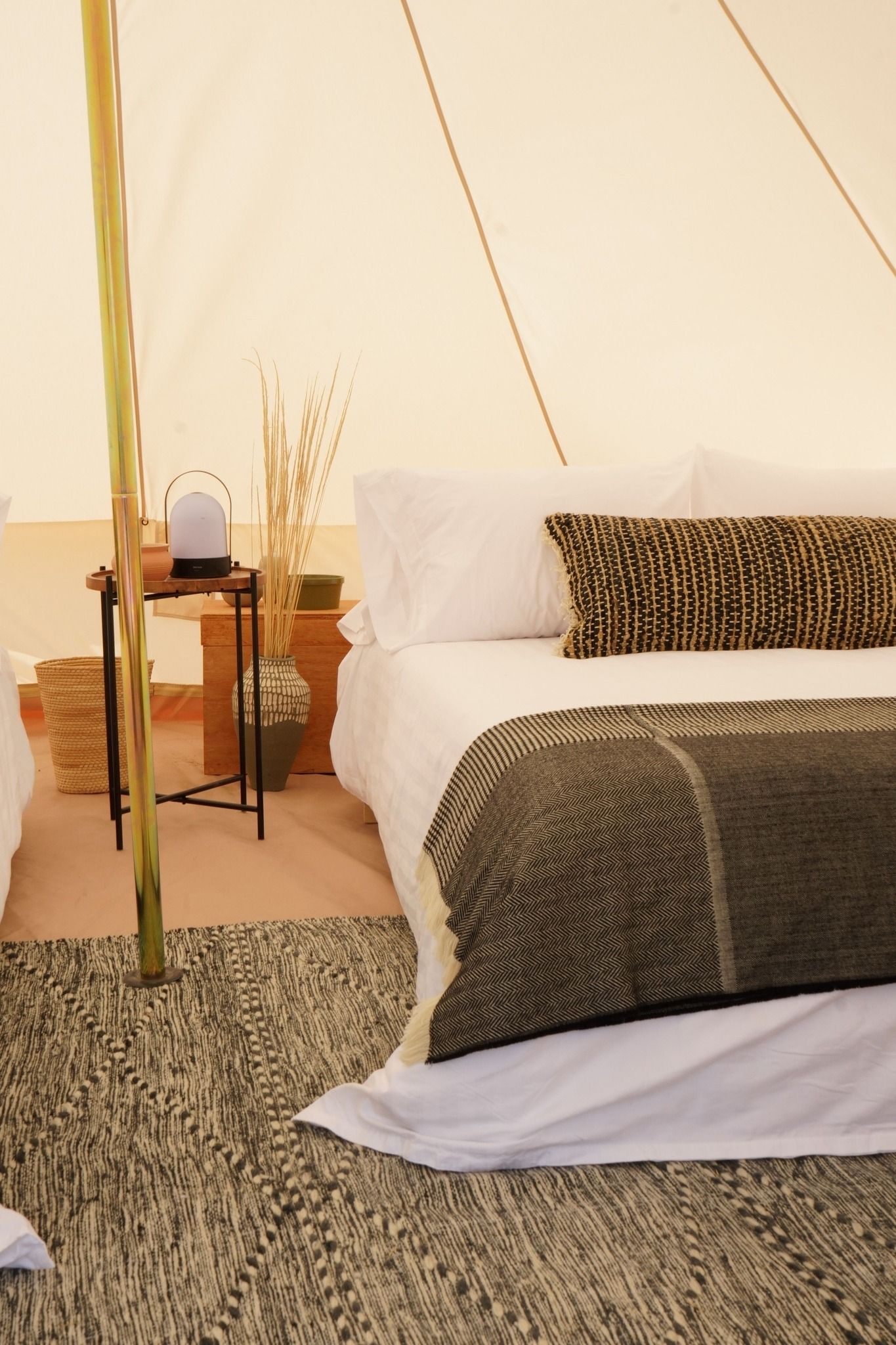 Una cama en una tienda de campaña con sábanas y almohadas blancas