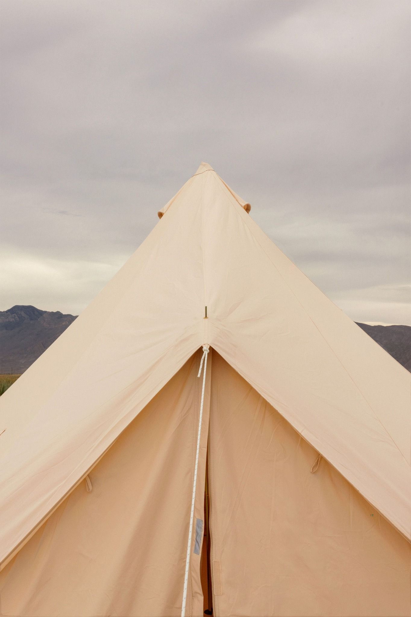 Una tienda de campaña está situada en el desierto con montañas al fondo.