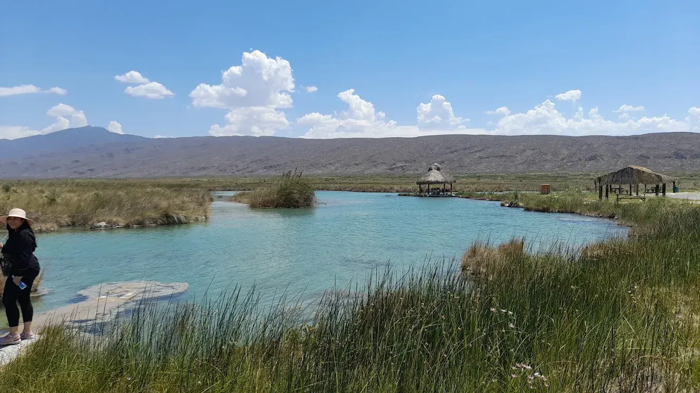 Una mujer está parada en la orilla de un lago.