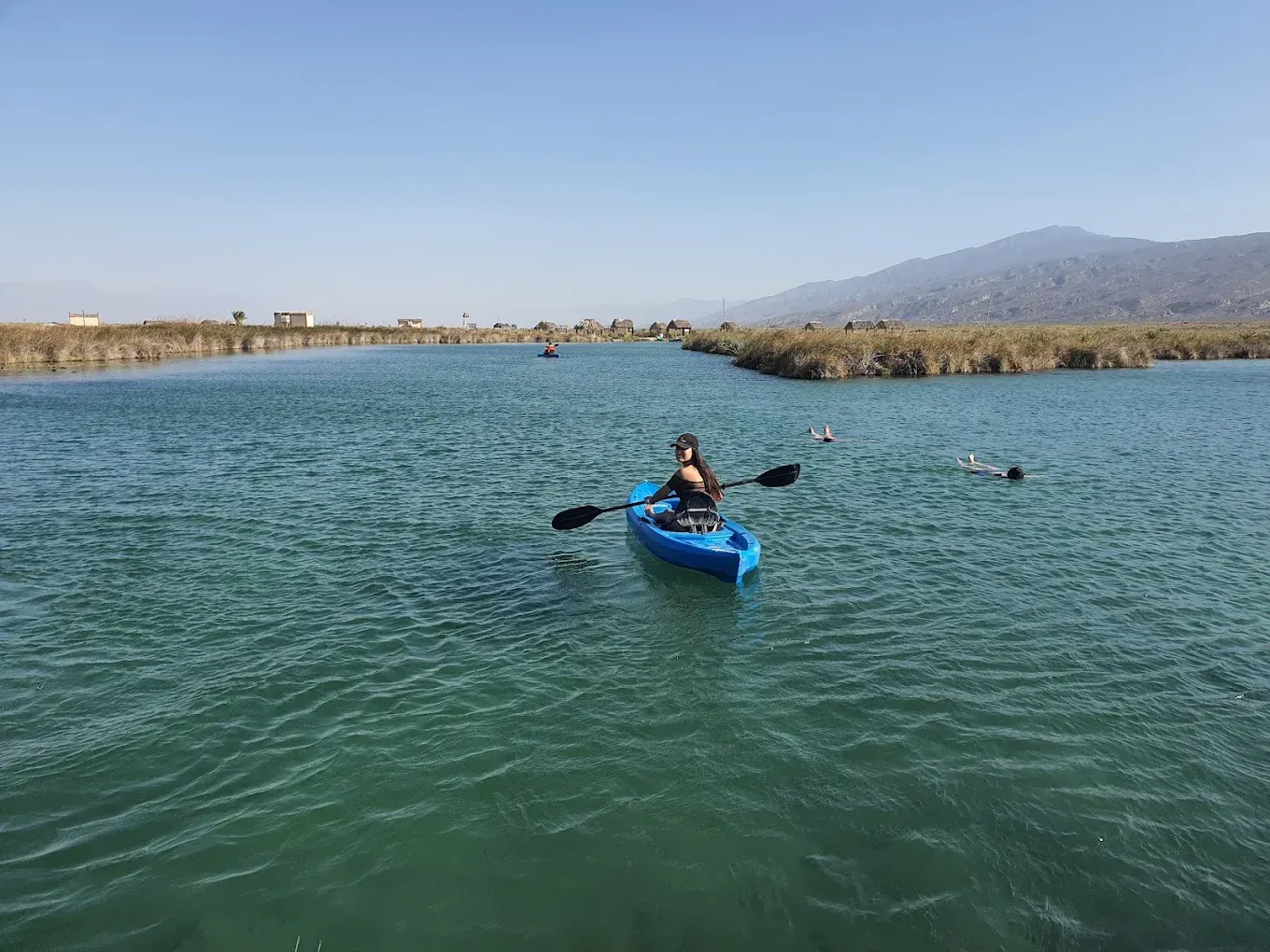 Una persona está remando en un kayak azul en un lago.
