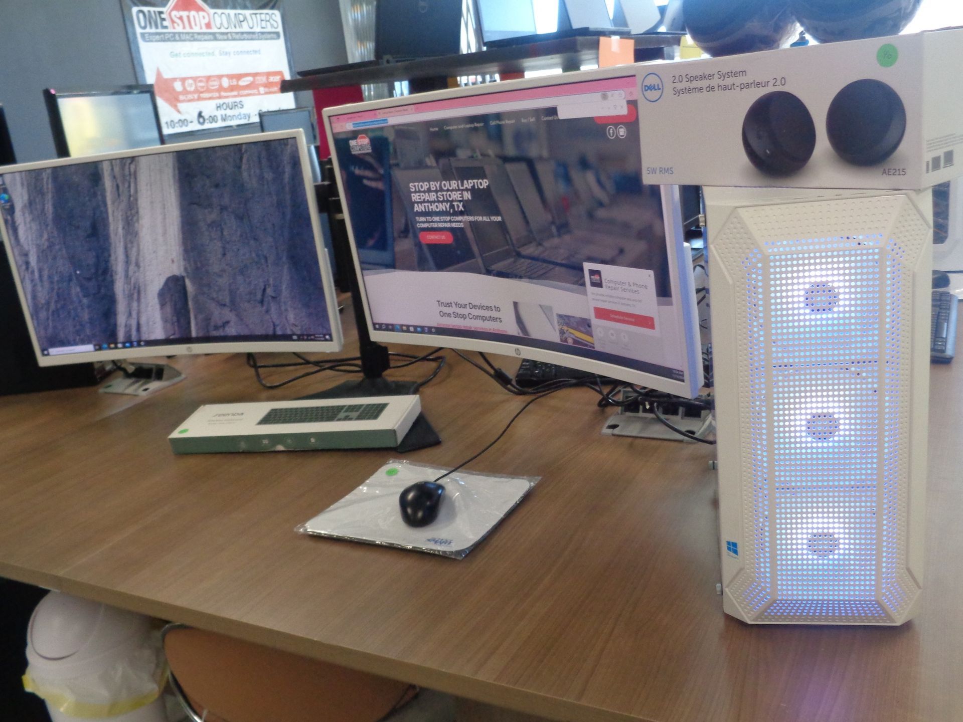 A computer setup with two monitors, mouse, and a tower case. The case has blue lights.