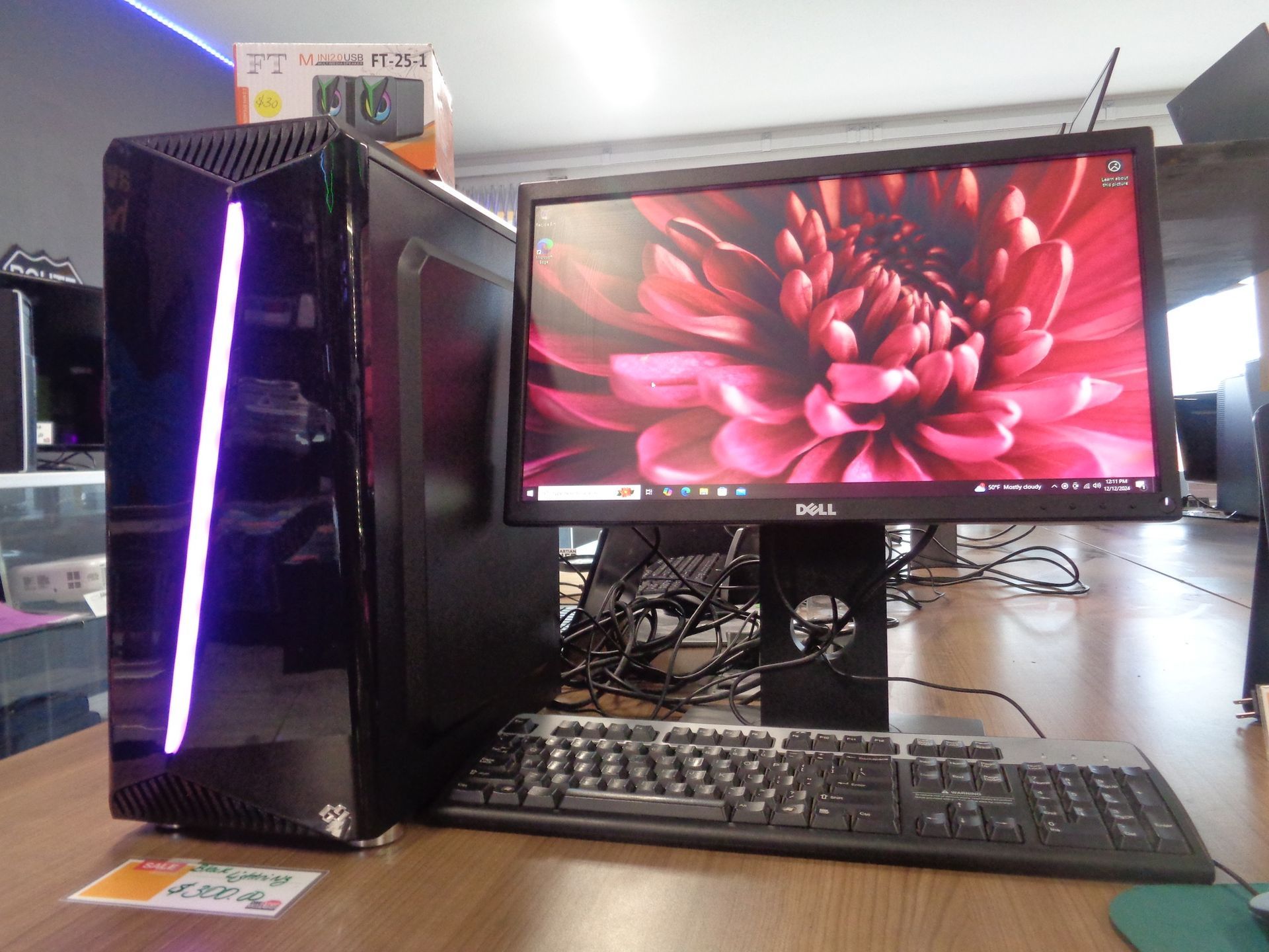 Black desktop computer with monitor, keyboard, and mouse on a wooden surface.