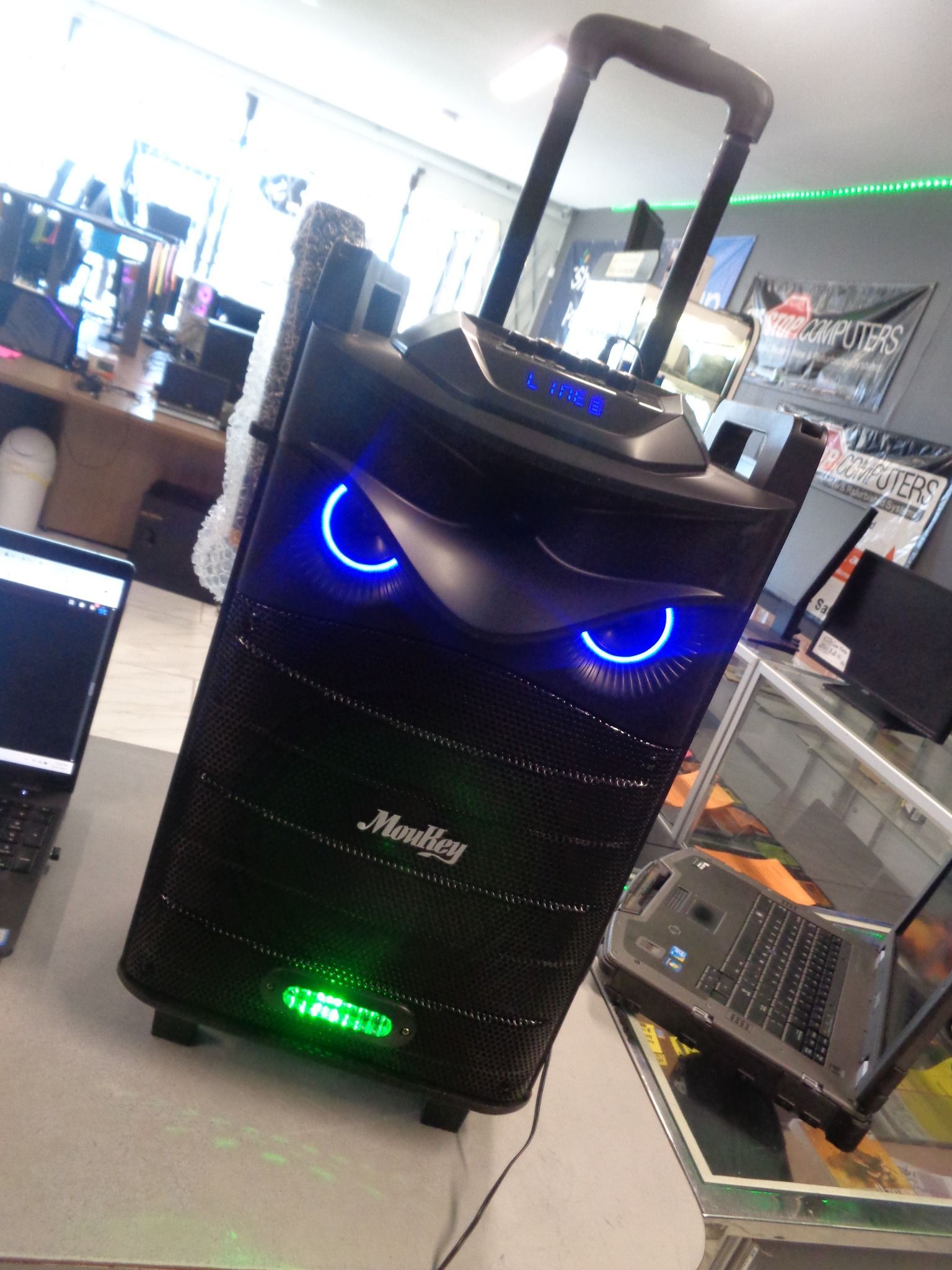 Black speaker with blue and green lights, handle extended.