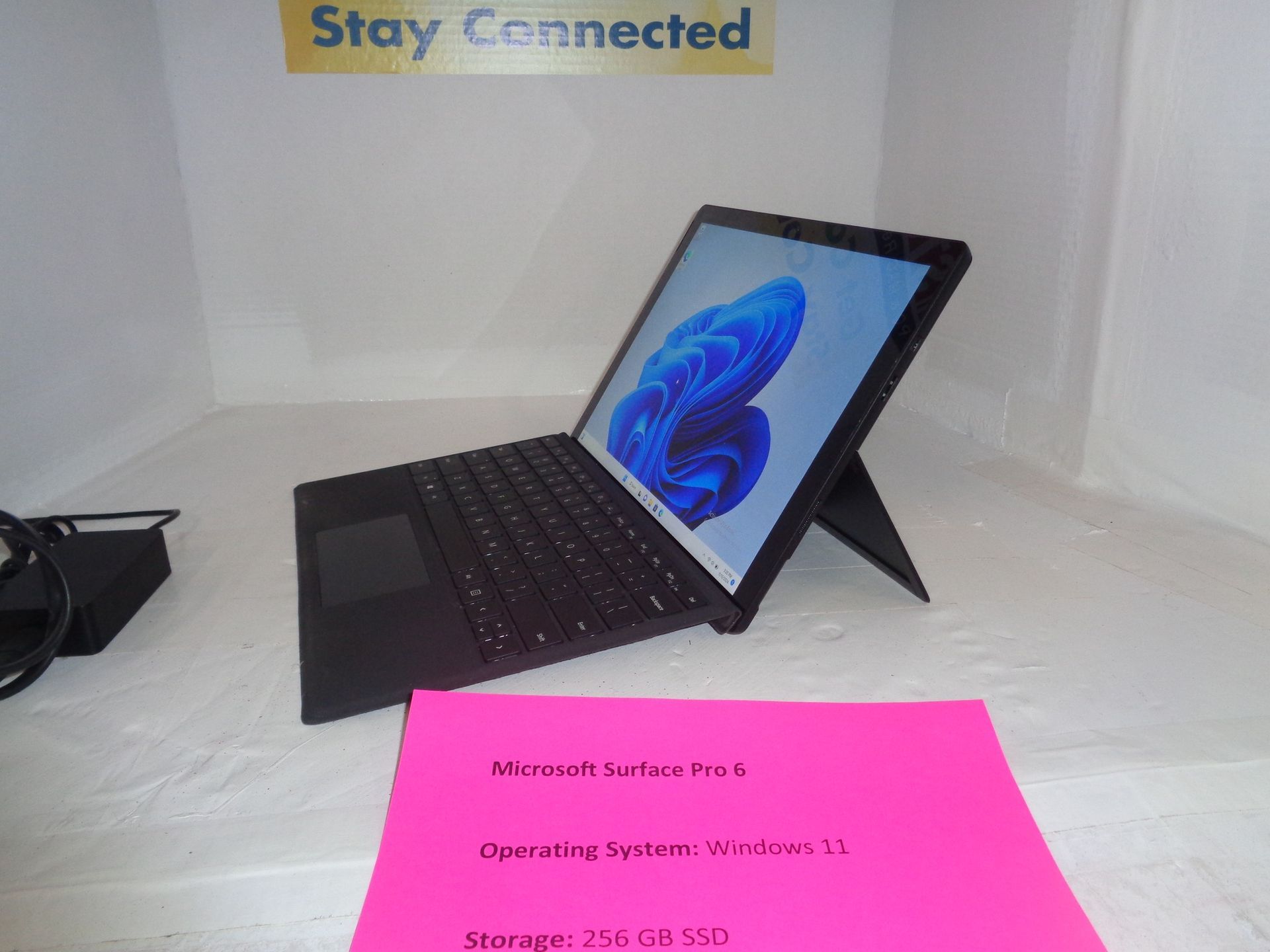 Black Microsoft Surface laptop with Windows 11 on a white surface, propped up with the kickstand.