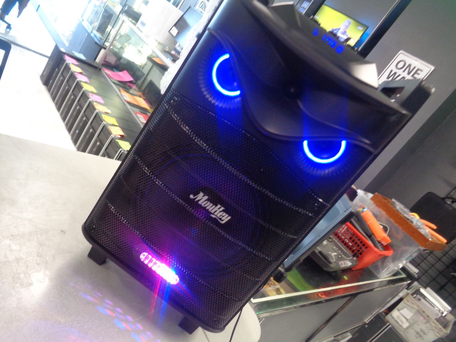 Black speaker with glowing blue owl-like eyes and logo, on a store counter.
