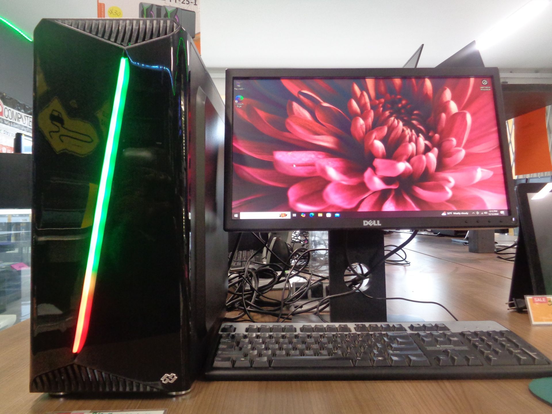 Black computer tower and monitor with keyboard. Screen displays a flower image.