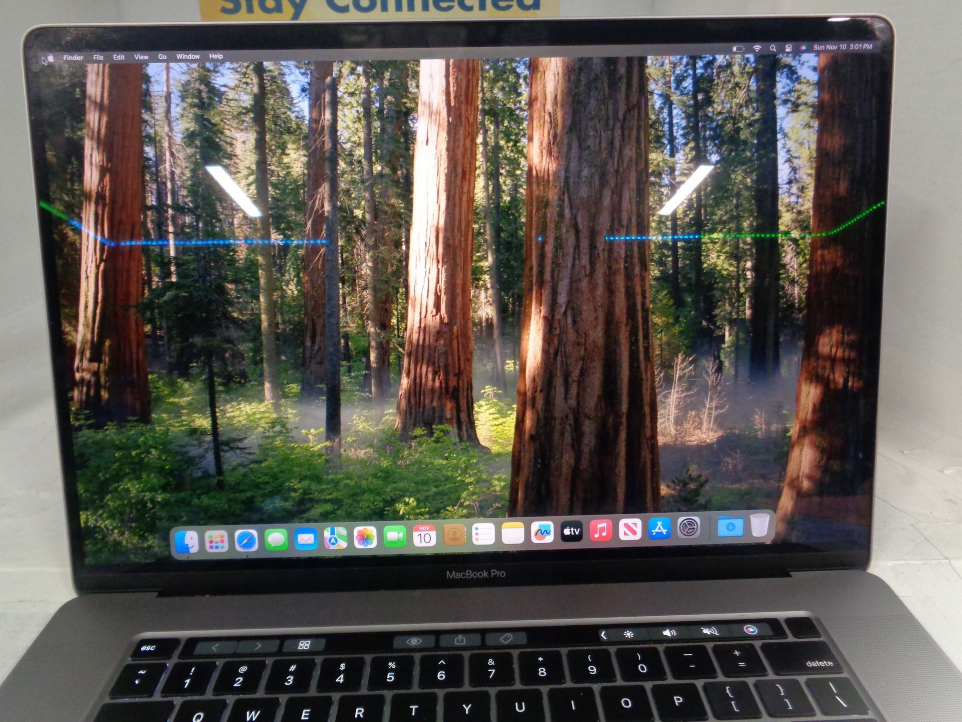 Laptop with a forest scene background, displaying a row of app icons.