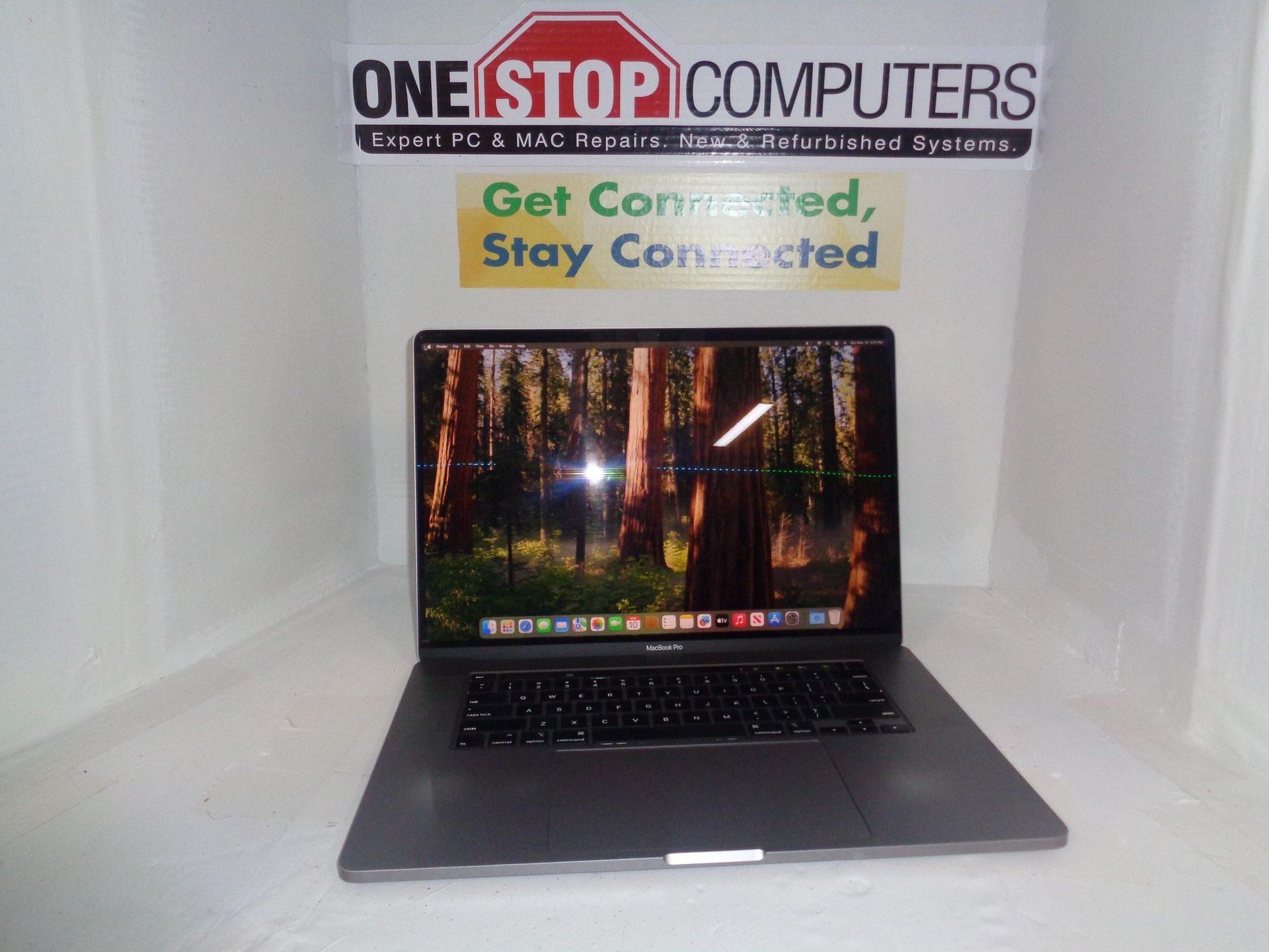 Laptop on a white surface with a forest wallpaper; 