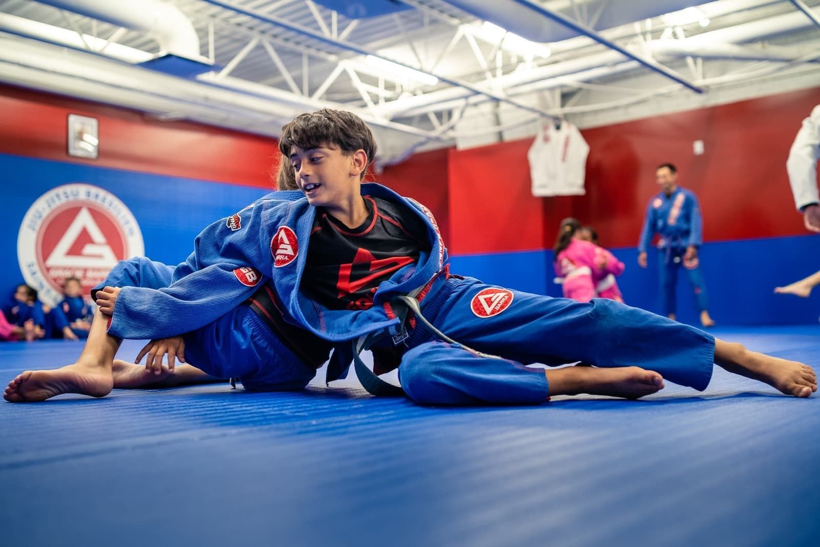 A group of young boys are practicing jiu jitsu in a gym.