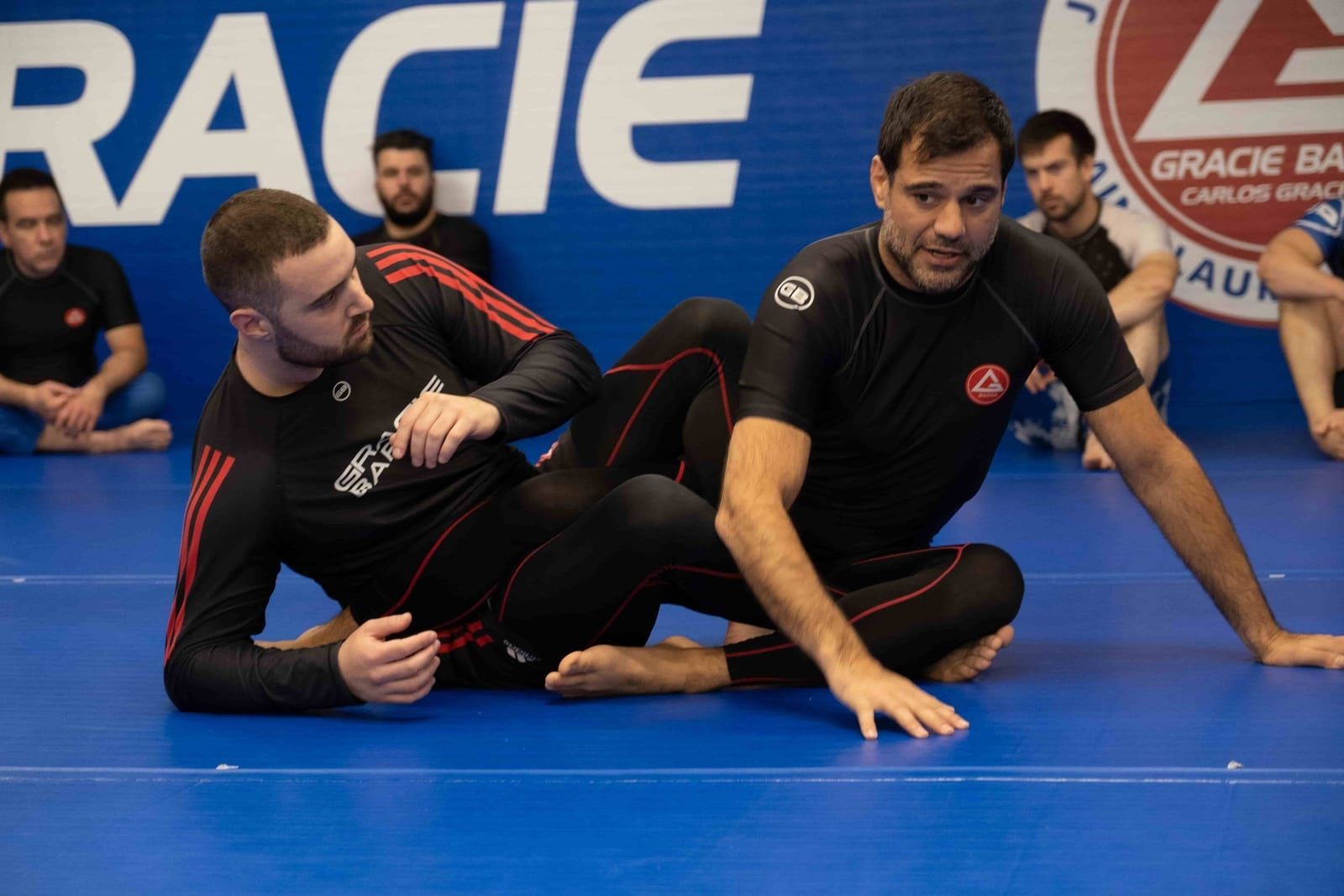 Two students practicing leg lock escapes.