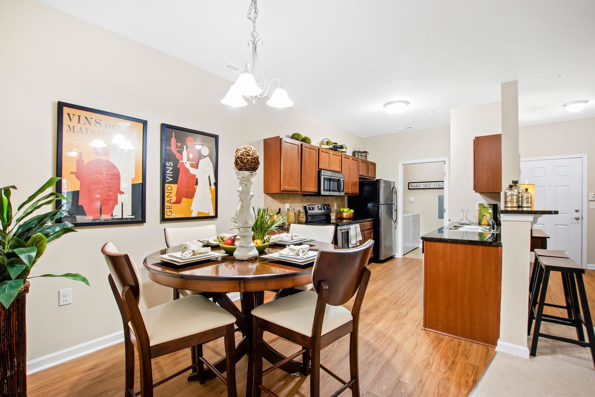 Open-concept dining area with round wood table and chairs beside a modern kitchen.