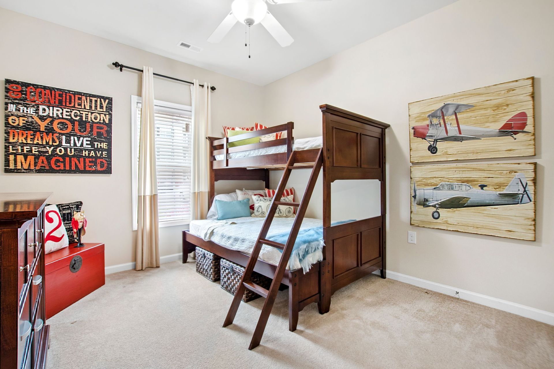 Bedroom with dark wood bunk bed, ladder, dresser, and aviation-themed wall art.