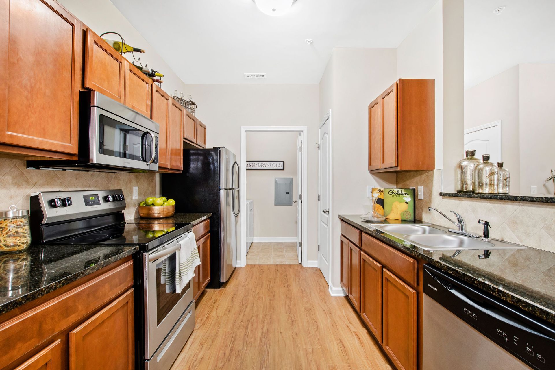 Kitchen in an apartment with wooden cabinets, black granite countertops, and stainless-steel appliances.