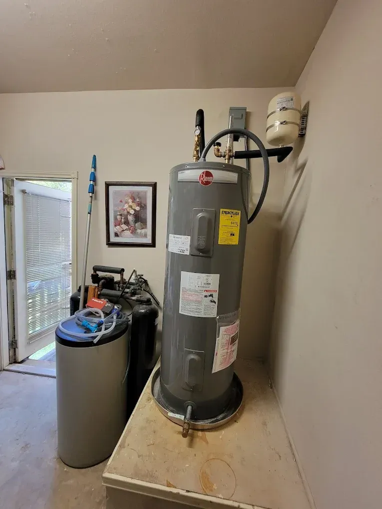 A gray water heater is sitting on top of a wooden table in a room.