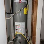 A water heater is sitting in a room next to a wall.