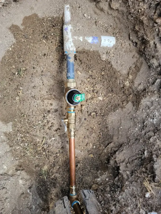 A close up of a copper pipe in the dirt.