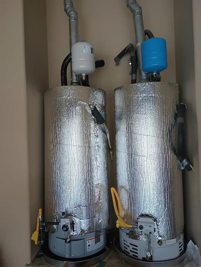 Two water heaters are sitting next to each other in a room.