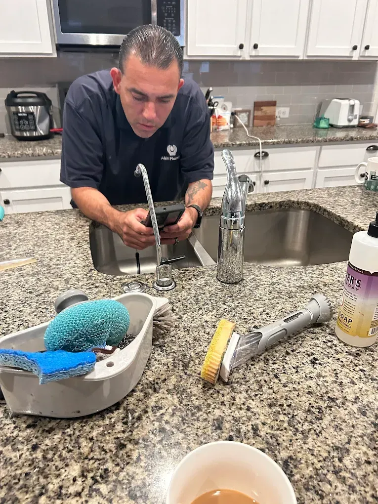 A man is fixing a faucet in a kitchen.
