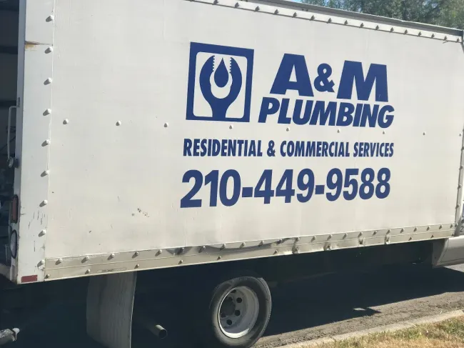 A white a & m plumbing truck is parked on the side of the road