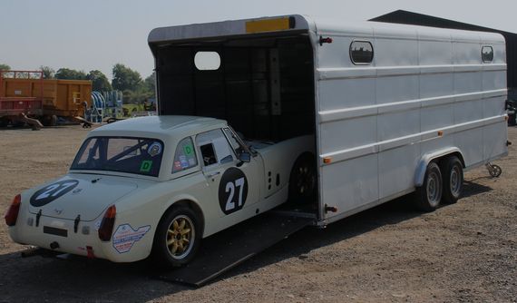 A sports car being loaded into a covered car trailer