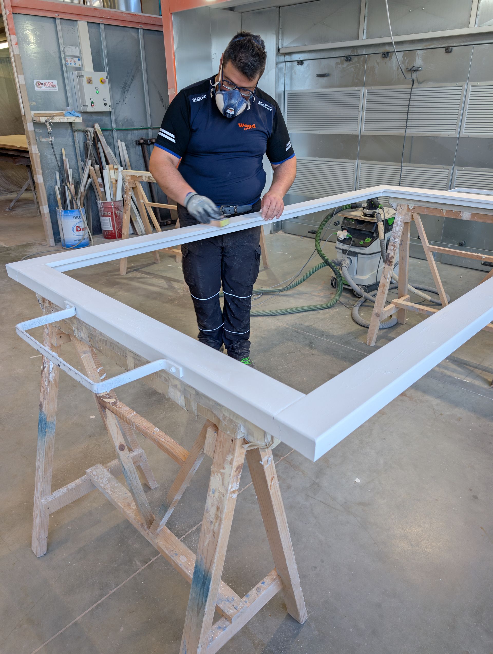 Un uomo sta dipingendo il telaio di una finestra in un'officina.
