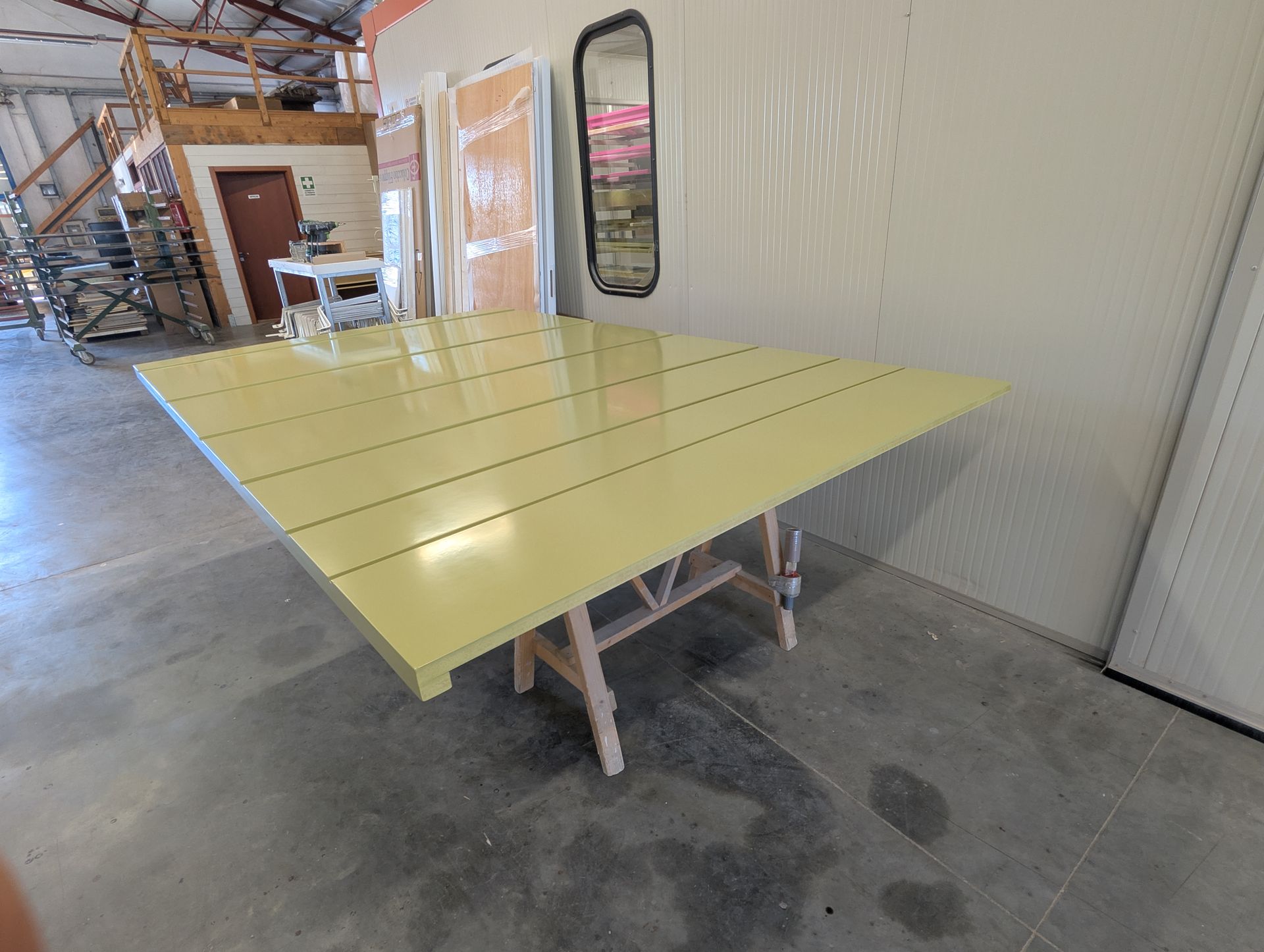 In una stanza c'è un tavolo giallo accanto a uno specchio.