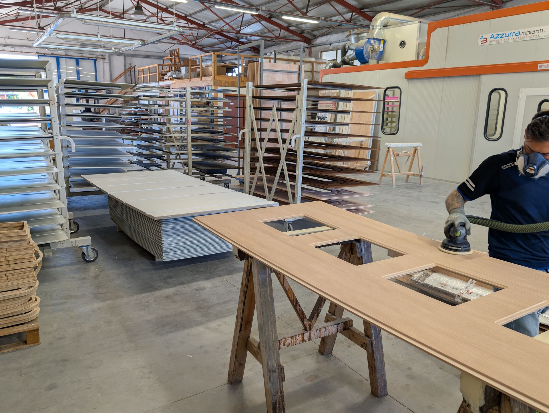 Un uomo sta levigando un pezzo di legno in un magazzino