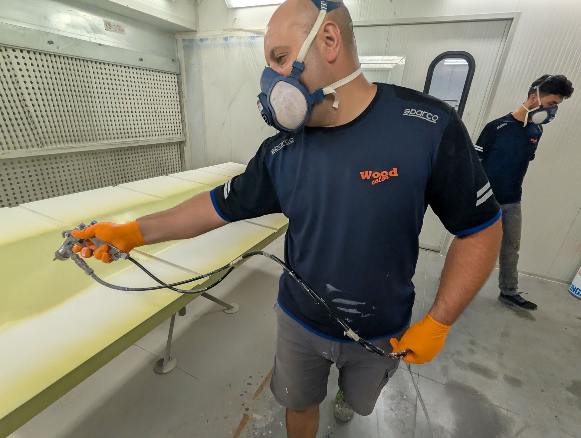 Un uomo che indossa una maschera sta spruzzando vernice su un tavolo.