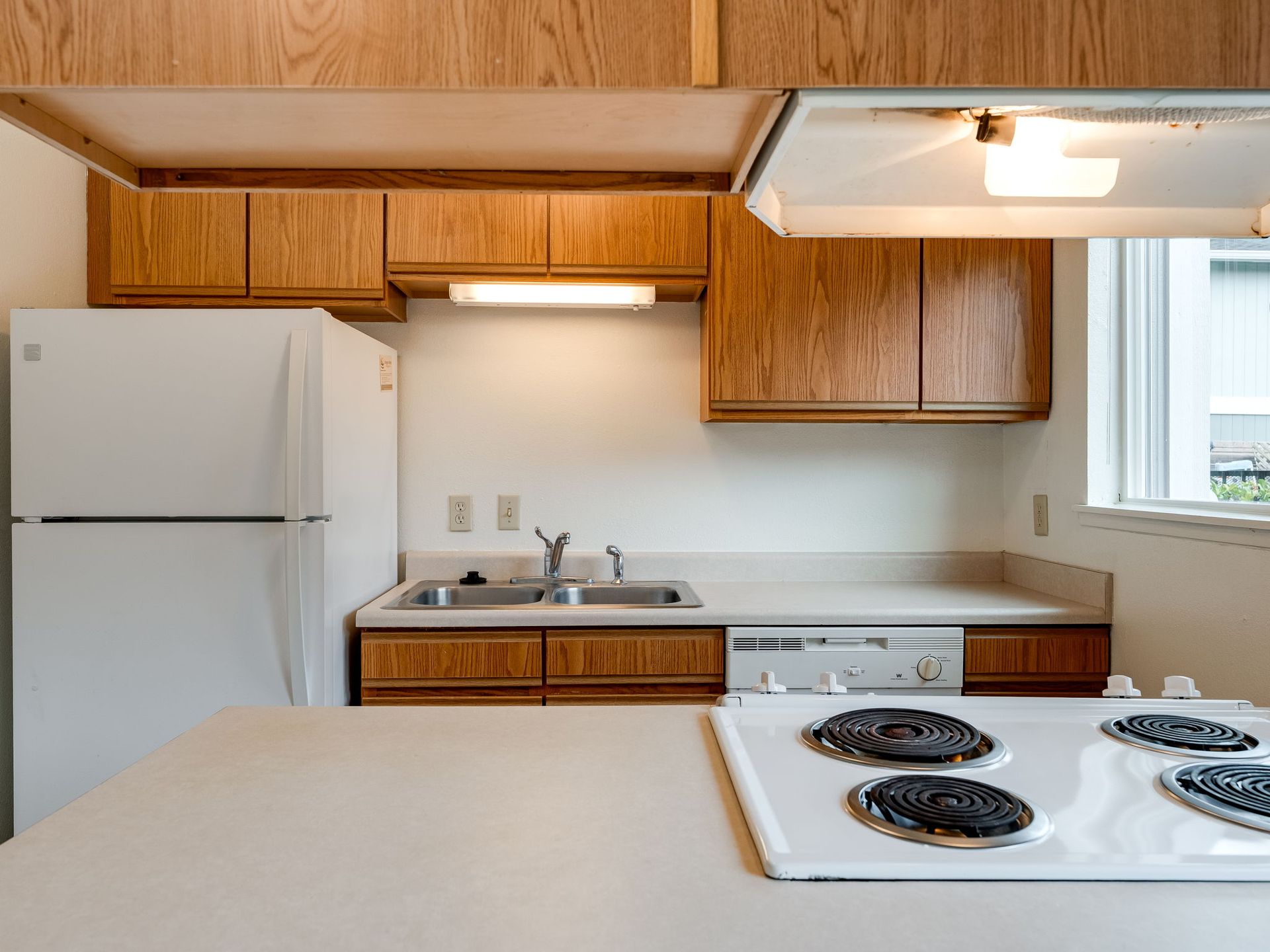 Southridge Apartments Townhome kitchen with view of stovetop and refrigerator, sink, diswasher in the background.