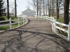 A Driveway With A White Fence And A Garage In The Background | Manilla, IN | Floyd Crim & Sons Paving