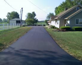 A Asphalt Driveway Leading To A House With A White Fence | Manilla, IN | Floyd Crim & Sons Paving