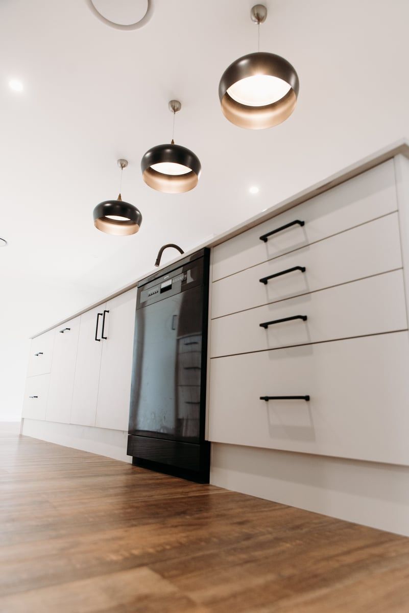 A kitchen with white cabinets and a black dishwasher