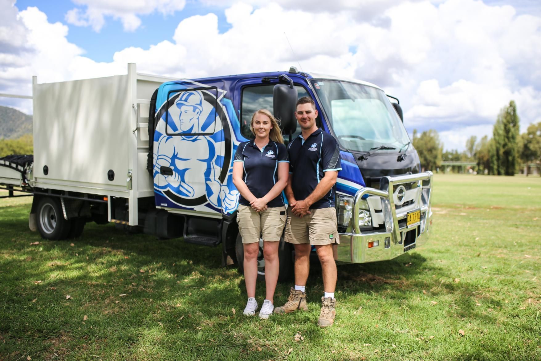 A man and a woman are standing in front of a truck.