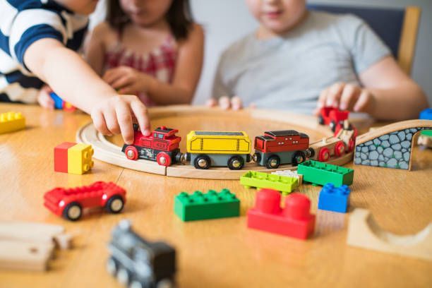 Close-up of little children playing with blocks, trains and cars, in a childcare center.