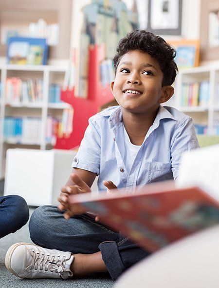A young boy is sitting on the floor reading a book.