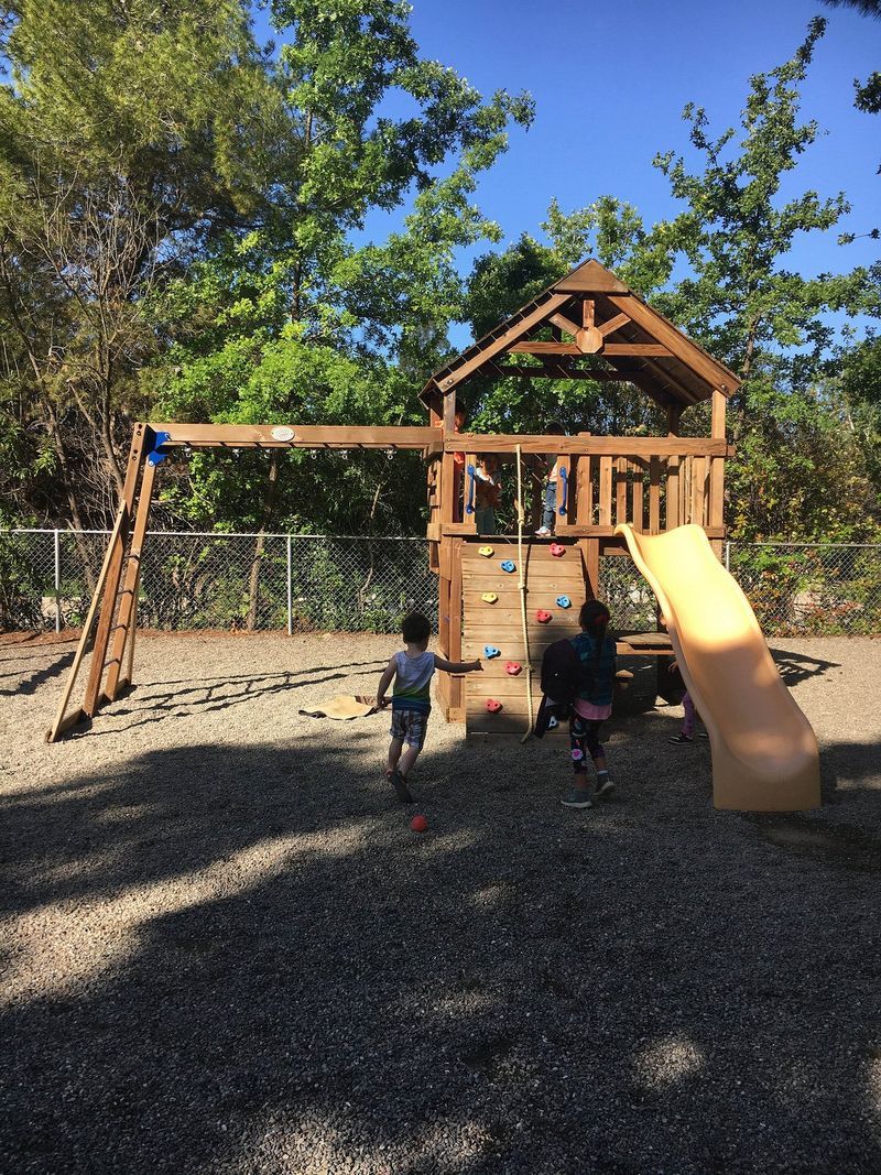 Two children are playing on a playground with a slide.