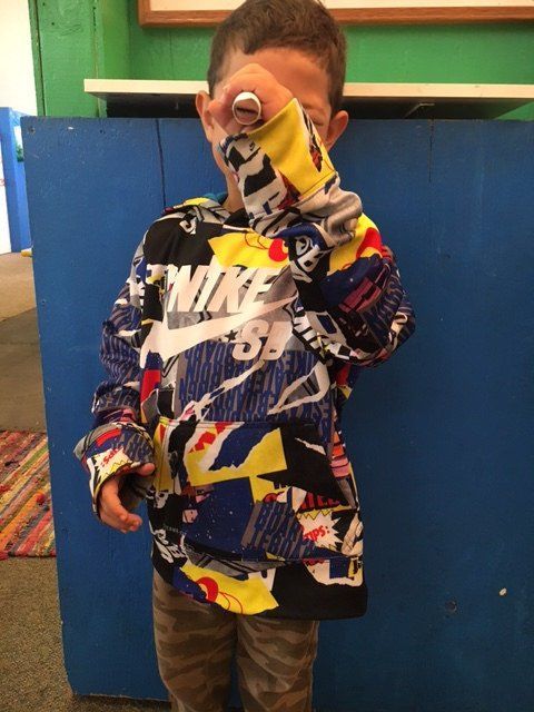 A young boy wearing a nike shirt covering his face
