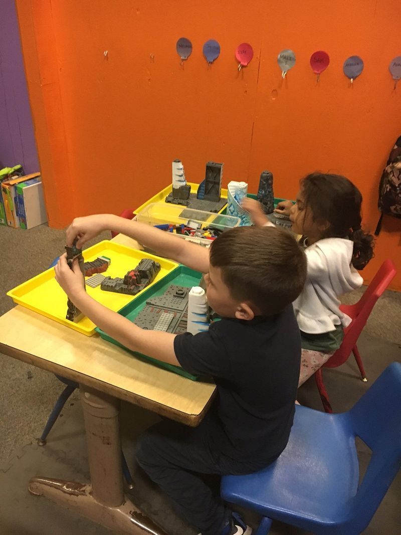 A group of children are sitting at a table playing with toys.