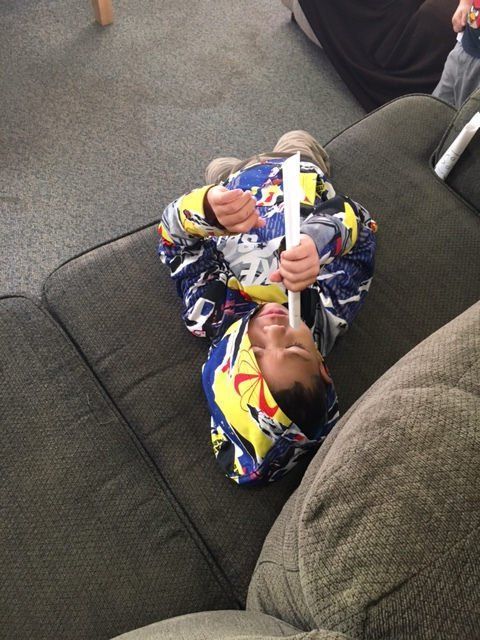 A child is laying on a couch holding a piece of paper