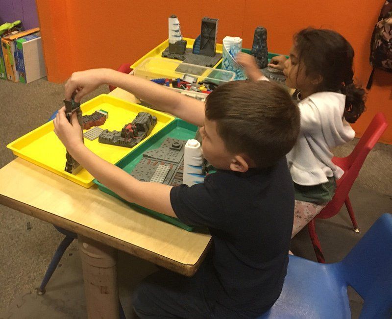 A boy and a girl are playing with toys at a table