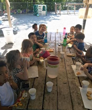 A group of children are sitting at a picnic table eating food.