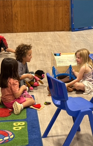 A group of children are sitting on the floor playing with toys.