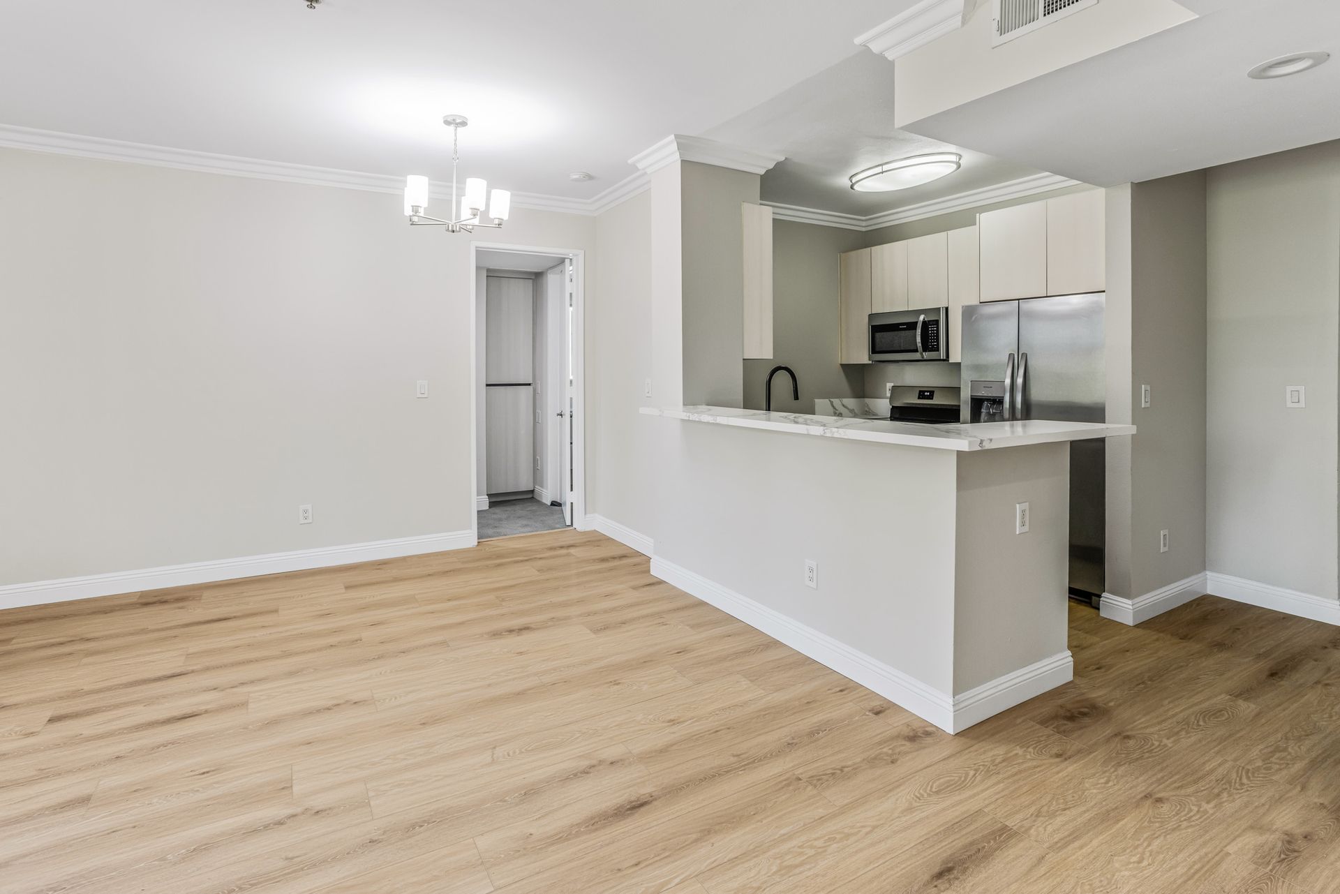 Empty open-concept living space with kitchen and wood floors.