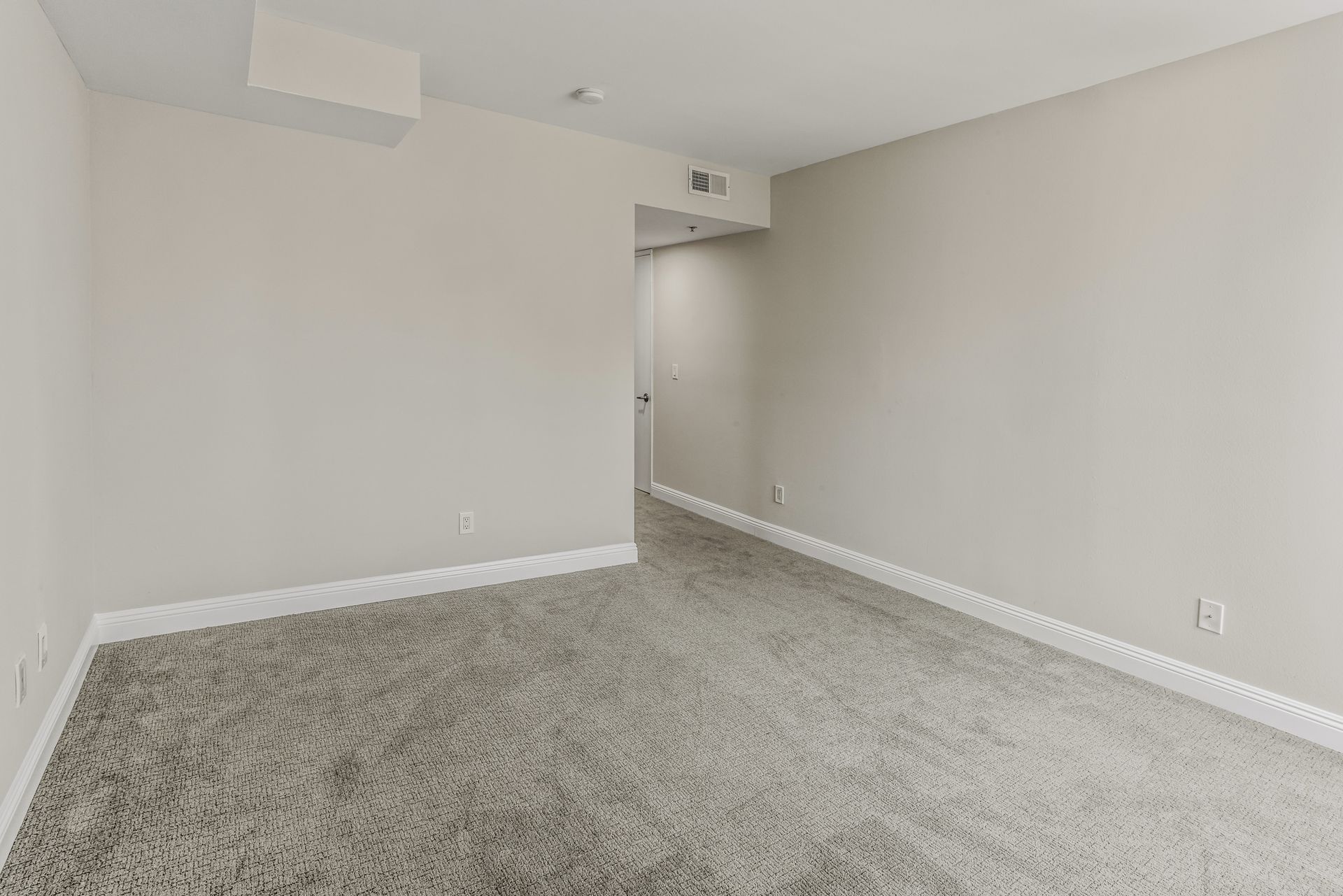 Empty room with gray carpet, white trim and walls, and an open doorway.